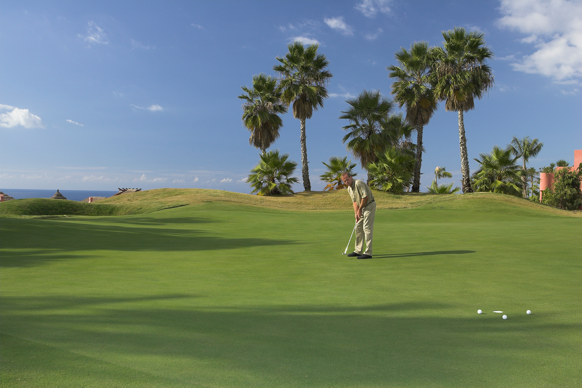 Gary Alliss watching his ball roll towards the hole on the green, with two other balls already settled by the hole as part of a distance control putting drill