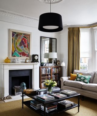 A living room with a white fireplace and a black ceiling light