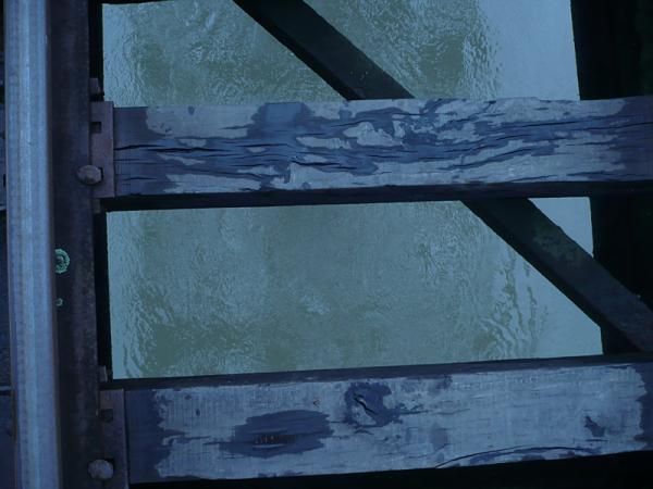 The view of the swollen river when looking down between railroad ties