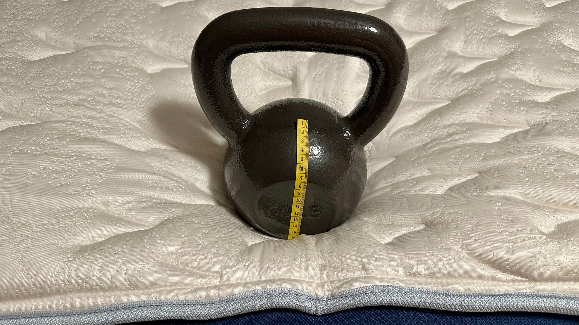 A kettlebell on the edge of the Glacier Apex Hybrid mattress to test its edge support