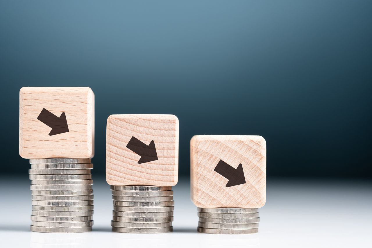 Descending finance graph, decrease coins heap with arrow sign on wood block as graph symbol, business and econnomic recession, credit decrease or less saving money