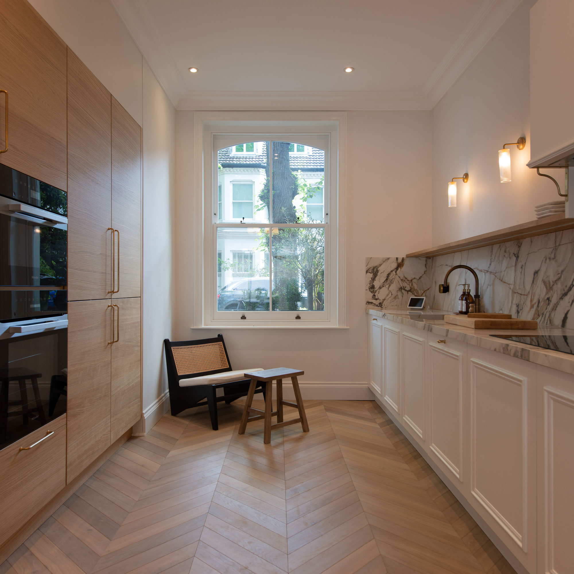 modern wooden kitchen with marble worktops and splashback and herringbone wooden flooring