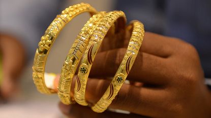 A hand holding gold bracelets