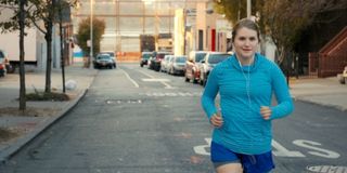 Brittany Runs A Marathon Jillian Bell running down the street, with headphones on