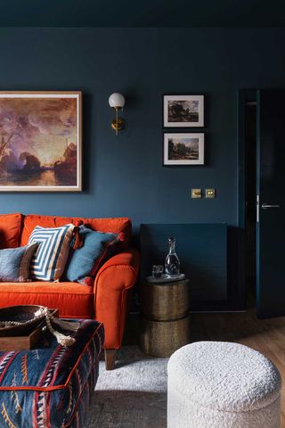 orange sofa and white footstool in a blue living room