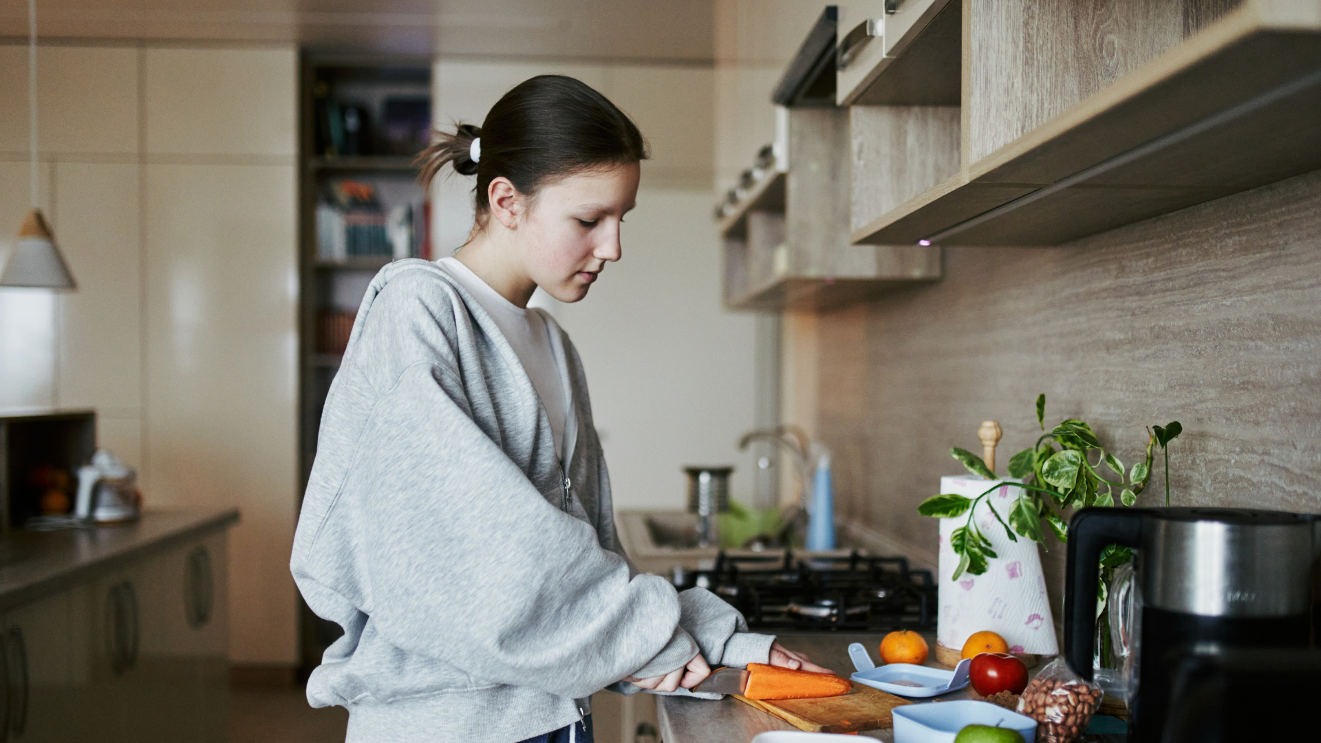 A teenage girl prepares vegetables to eat in a kitchen.