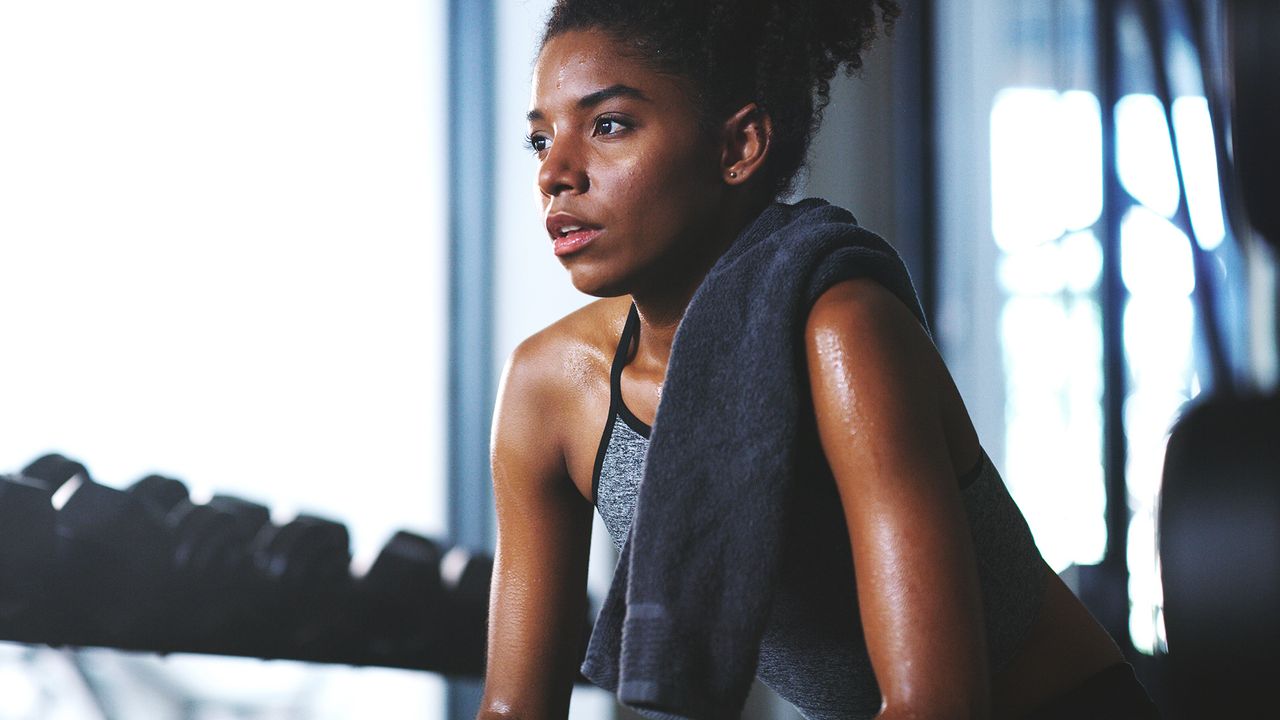 Woman with a towel over her shoulder looking sweaty after finishing a 40 ways to burn 400 calories workout