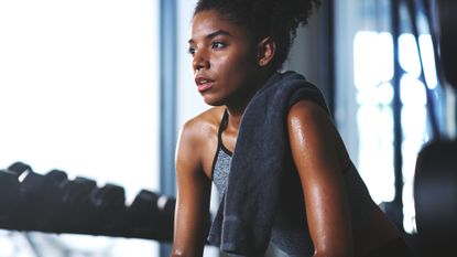 Woman with a towel over her shoulder looking sweaty after finishing a 40 ways to burn 400 calories workout