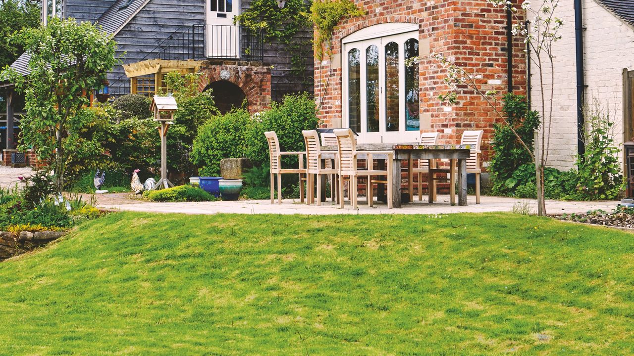 Sloped lawn in garden next to wooden outdoor seating area