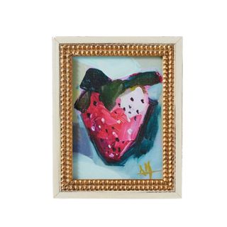A strawberry artwork with a gold frame