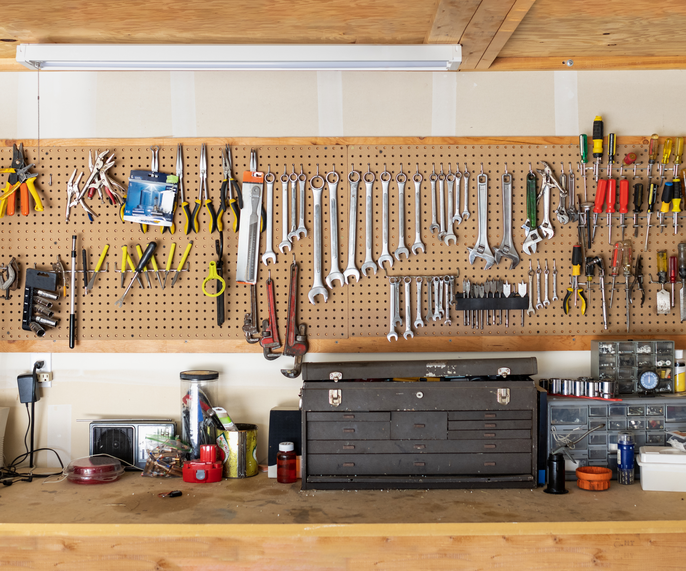 garage with taped plasterboard walls, tool storage and bench and plywood covered ceiling