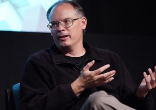 Tim Sweeney sits on a stage, gesturing with his hands.