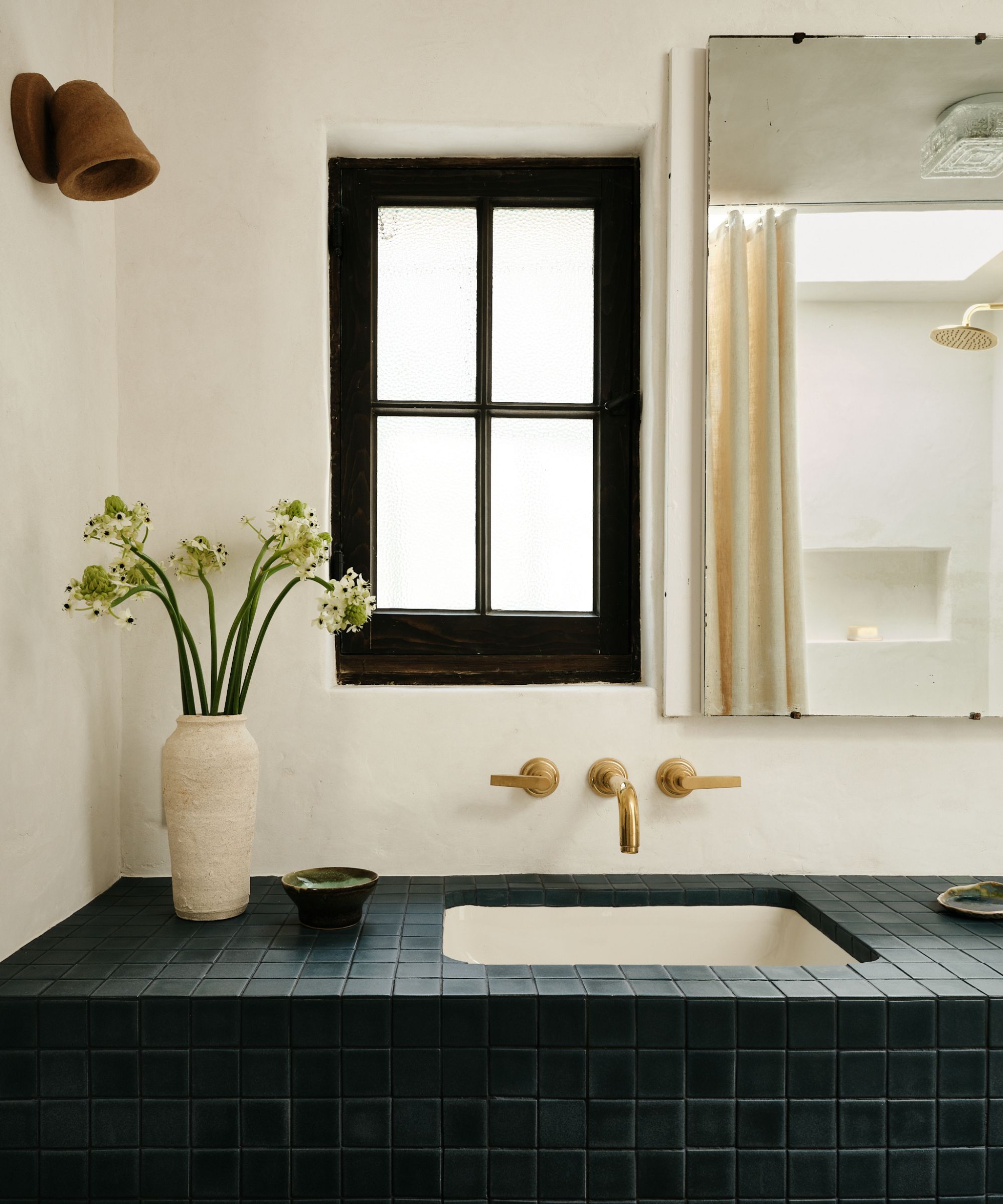 An adobe bathroom with a tiles vanity, plaster walls, and a medicine cabinet on the wall