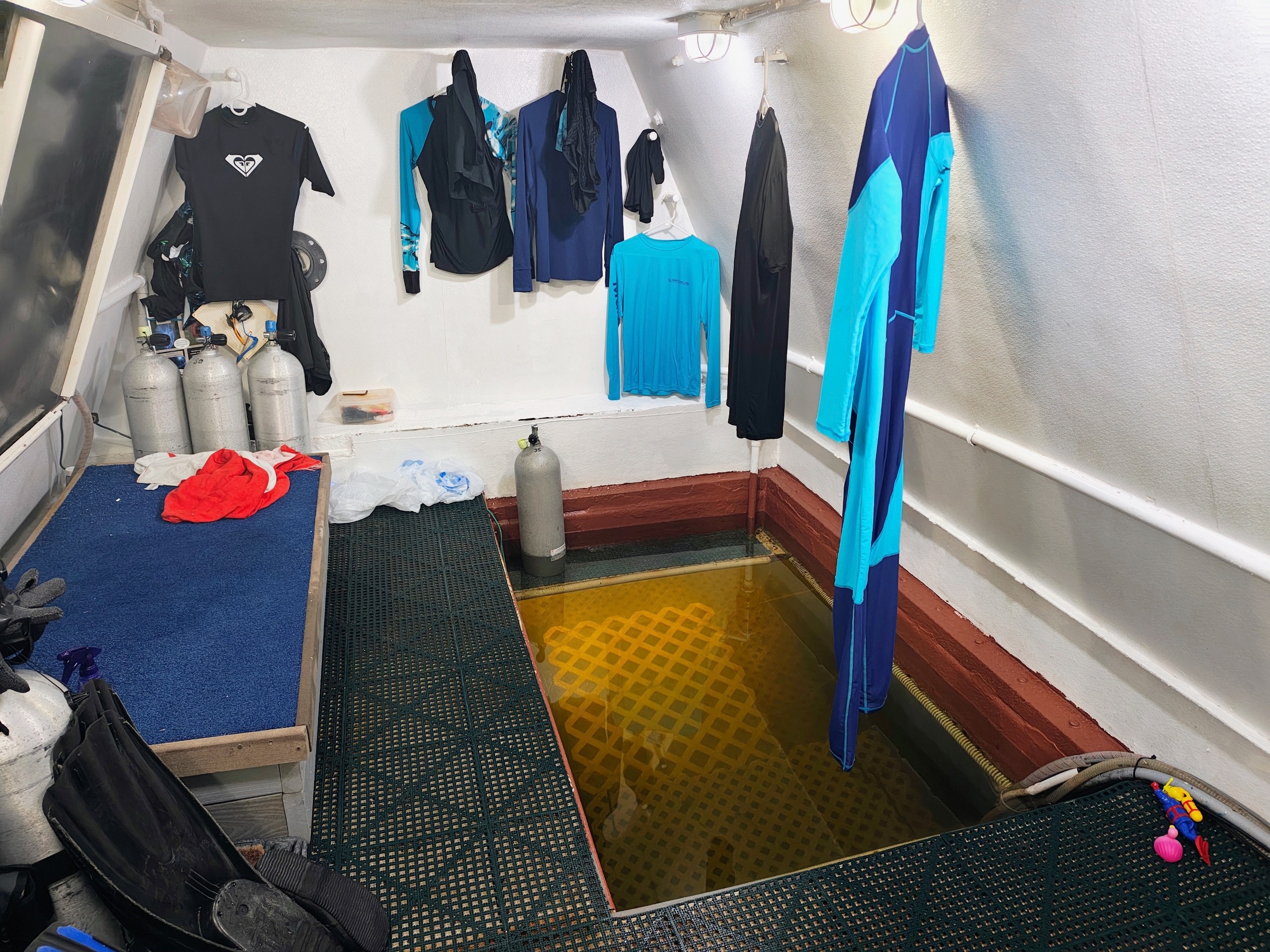 foto dentro de uma pequena sala de uma estação de pesquisa, mostrando roupas de mergulho e equipamento de mergulho dispostos ao longo das paredes