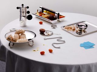 Silverware on white table cluttered with food and drink