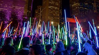 Photo of Star Wars fans holding up different color lightsabers.