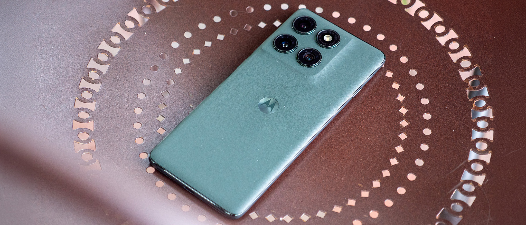 The vegan leather back of the forest green Motorola Edge 2025 on a brown metal chair
