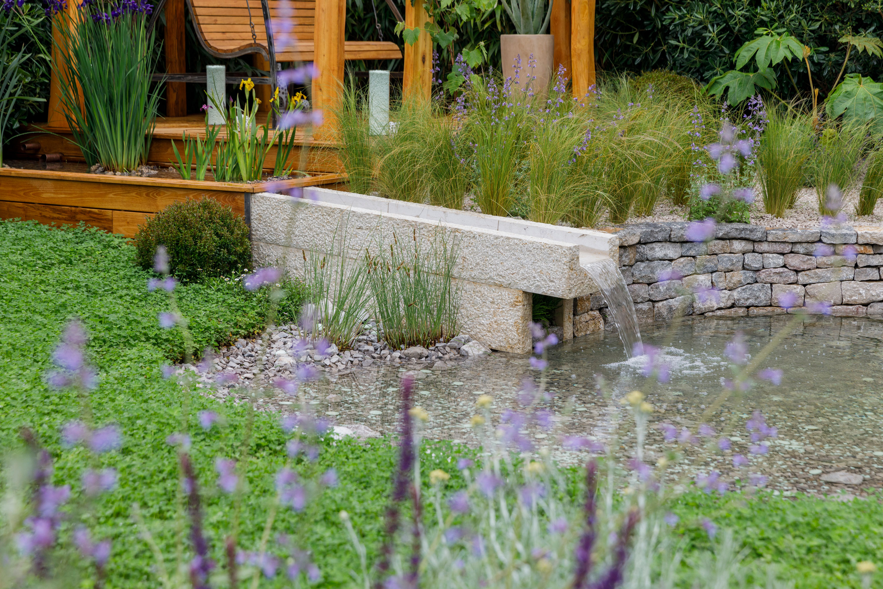 clover lawn with water feature and pergola with garden furniture