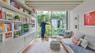 A homeowner standing with her two dogs looking out of her first floor living area through floor to ceiling glazed sliding windows