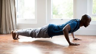 Man doing a burpee or plank in his front room