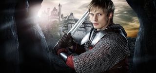 Bradley James as King Arthur wielding a sword