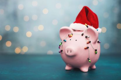 Piggy bank wearing Santa hat and wrapped in Christmas lights