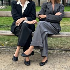 detail image of two women wearing black ballet flats and pant suits