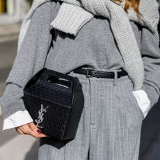 Woman wearing a grey jumper, carrying a YSL take-away box bag