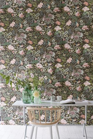 office space with floral wallpaper, white floorboards, desk, chair, vases of flowers
