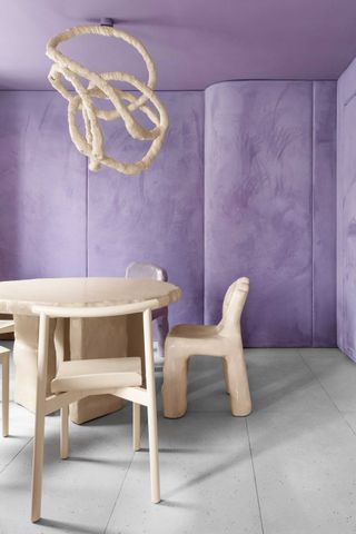 a dining table in from of a lavender wall