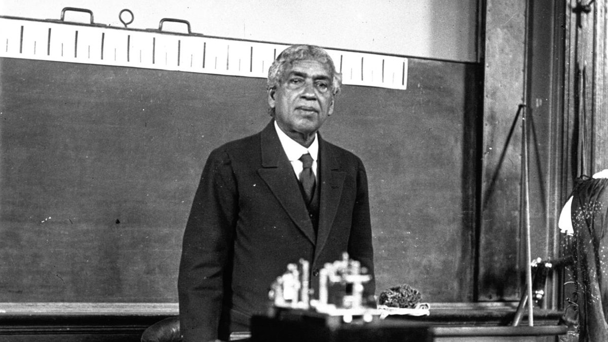 Black and white photo of Jagadish Chandra Bose standing in front of a blackboard.