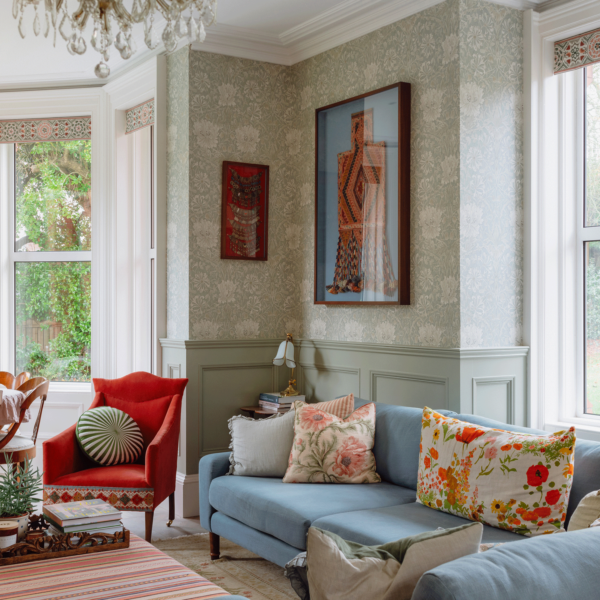 Green wallpaper and wall panelling with blue sofa and red arm chair