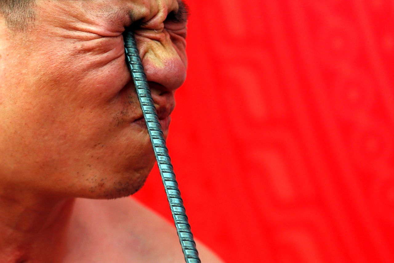 Ngo Chien Thuat, a traditional health worker, bends a metal pole by pressing it into his eye.