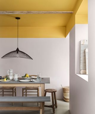 Dining area in kitchen with yellow painted ceiling extending down to top section of walls