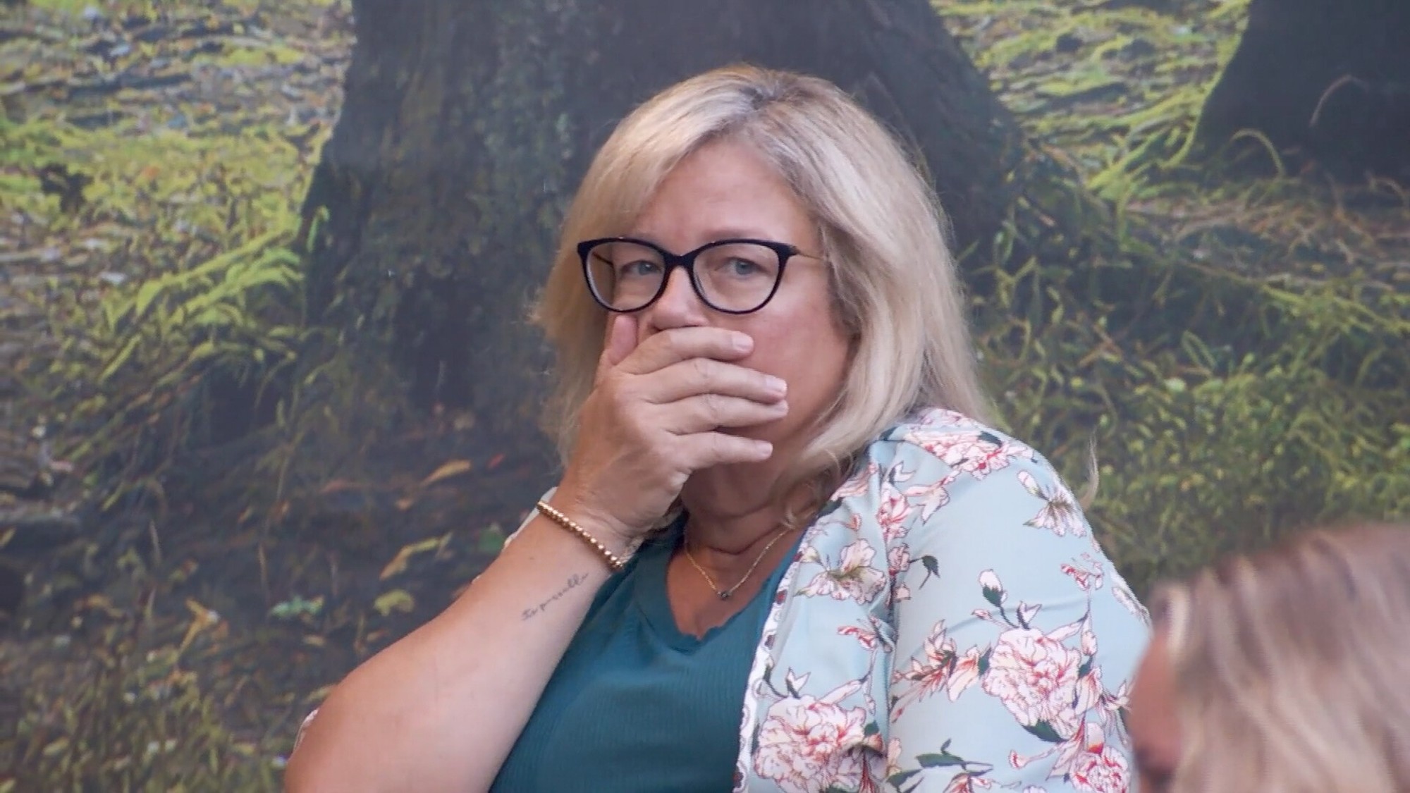 Angela covering her hand with her mouth.