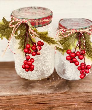 Two hand made frosted mason jar Christmas candle holders with berries and foliage
