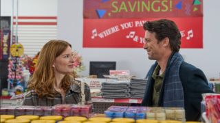 Stacey Farber and Daren Kagasoff smiling at each other behind a candle display at a party store