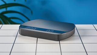 a luxury coffee scale made by Felicita Arc is photographed against a blue background with its weight, USB-C cable, and silicone mat