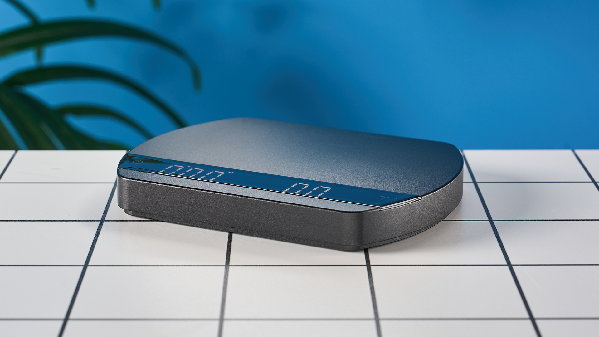 a luxury coffee scale made by Felicita Arc is photographed against a blue background with its weight, USB-C cable and silicone mat