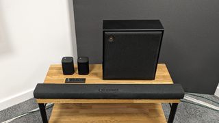Yamaha True X Soundbar System soundbar, surrounds, subwoofer and remote on wooden rack