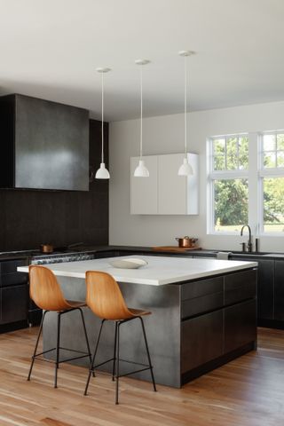 A black kitchen with a white island and wooden bar stools