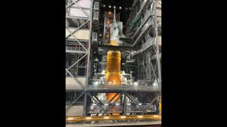 Engineers retract work platforms surrounding NASA's Space Launch System rocket as they ready to roll out the rocket to the launch pad.