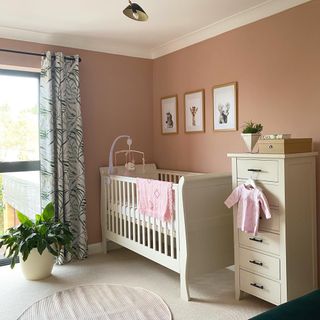 Nursery with pink painted walls and white furniture