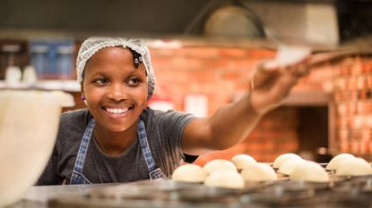 A small-businesswoman smiles at a bakery.