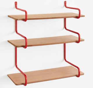 A wall shelf with red metal accent