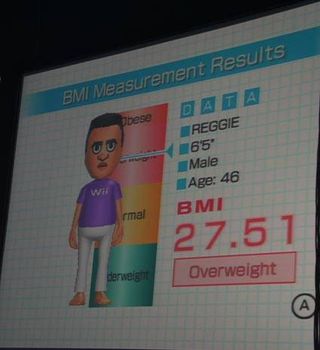 Reggie Fils-Aime gets his body mass index measured on the Wii Balance Board for WiiFit.