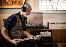 A retired man in his late 60s listens to vinyl records at home.