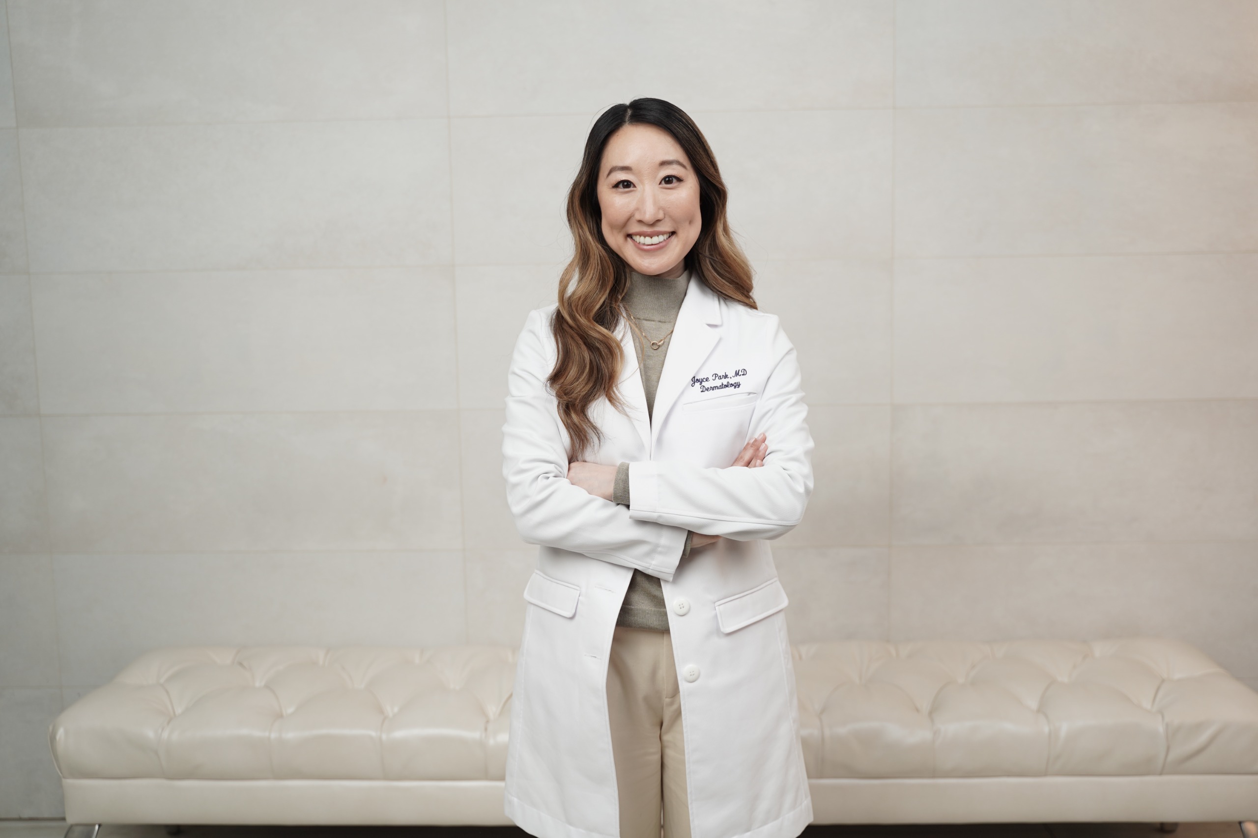 an asian woman in a white lab coat and green sweater