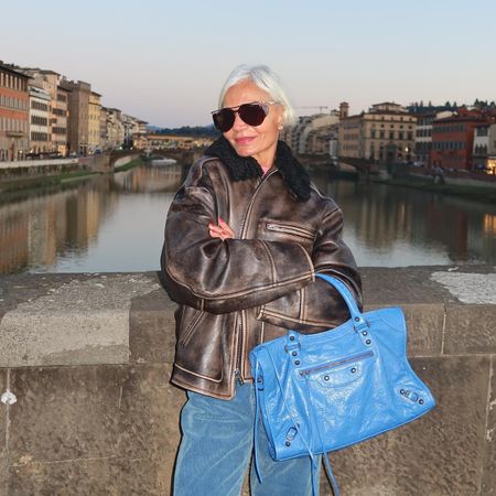 Grece Ghanem in a leather bomber jacket with a blue Balenciaga Le City bag.