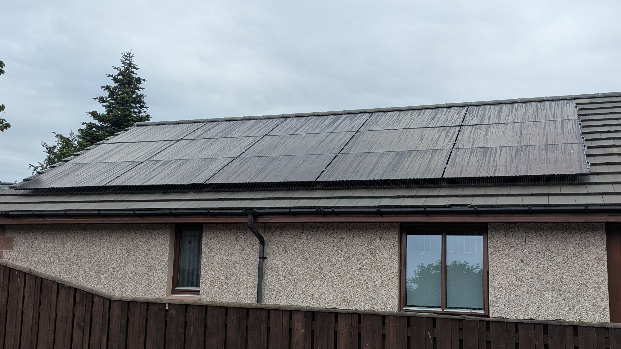 Solar Panels mounted on roof with streaks of rain visible, on a cloudy day